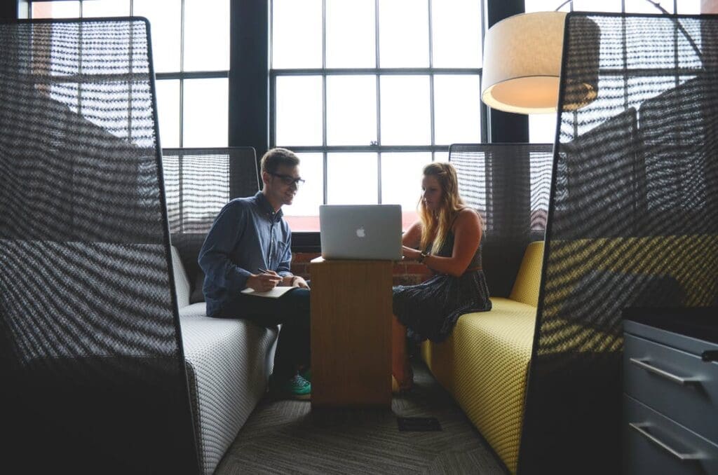 Man and woman in a professional meeting space, working on a laptop together