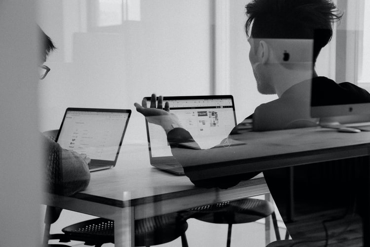 two colleagues sat with computers discussing projects 