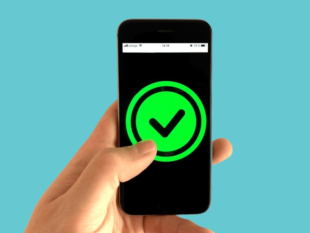 Person holding a mobile phone with a big green tick icon in the center