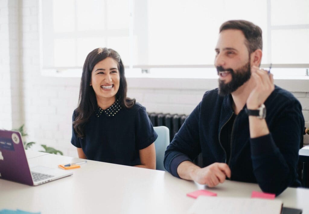 Man and woman in a bright office, smiling and talking during a meeting